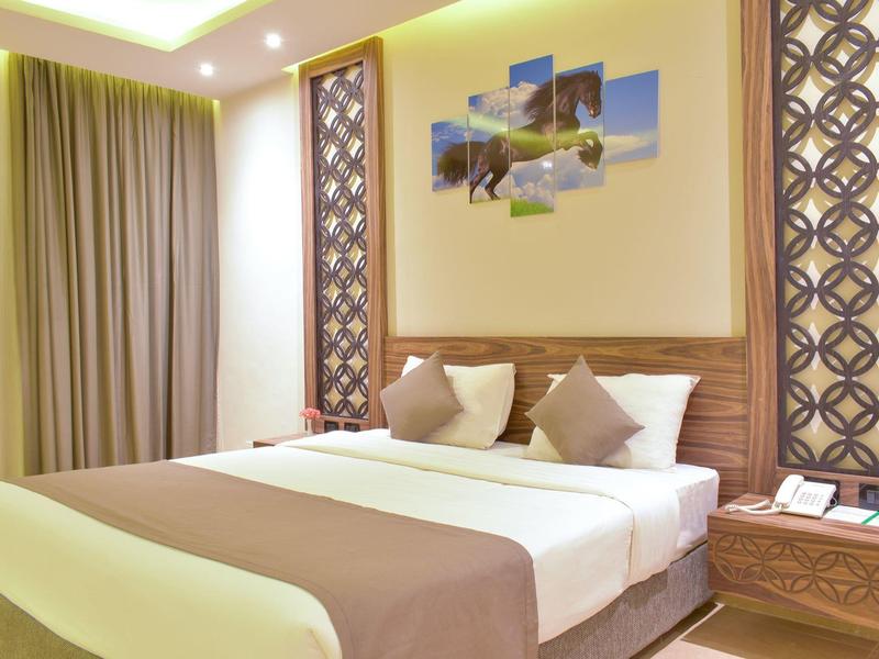 Modern eingerichtetes Schlafzimmer mit Doppelbett, braun-beiger Bettwäsche und dekorativen Paneelen.