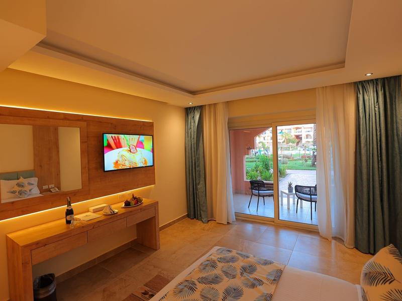 Helles Hotelzimmer mit Holzmöbeln, großem Spiegel, Fernseher und Balkon mit Straßenaussicht.