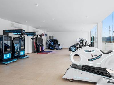 Helles Fitnessstudio mit modernen Geräten, großen Fenstern und minimalistischem, offenem Raumdesign.