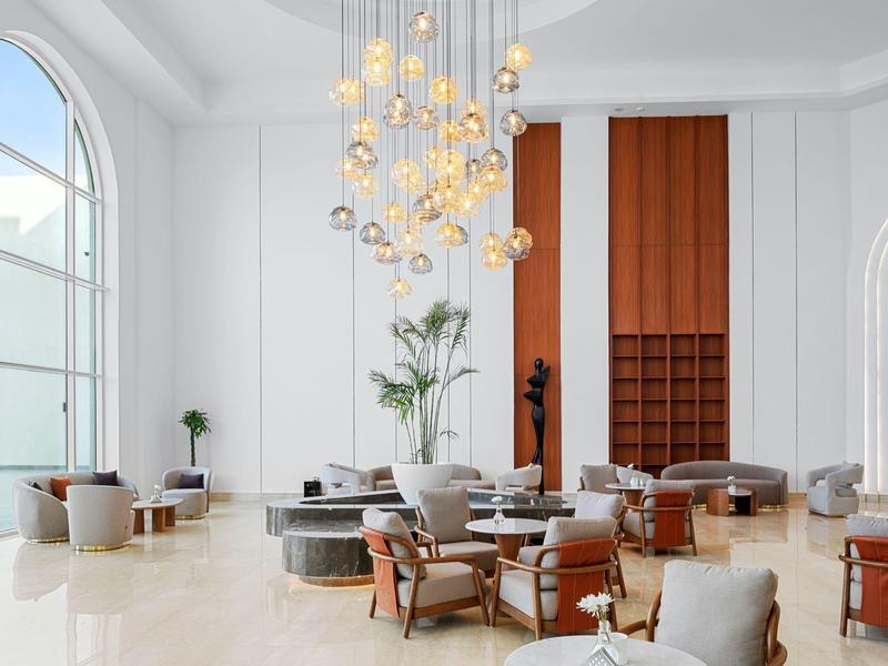 Eleganter Hotel-Loungebereich mit hohen Fenstern, Holzpaneelen und modernen Sitzmöbeln.