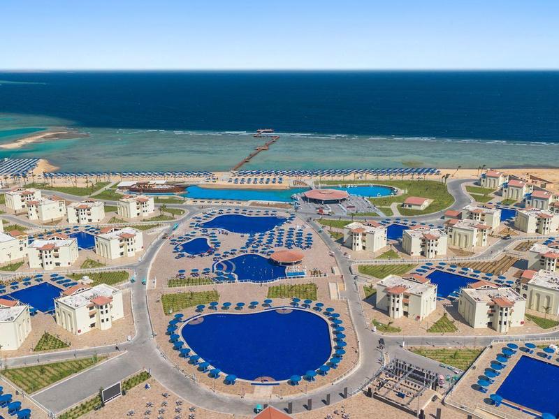 Luftaufnahme einer weitläufigen Ferienanlage mit mehreren Pools und Blick auf das Meer.