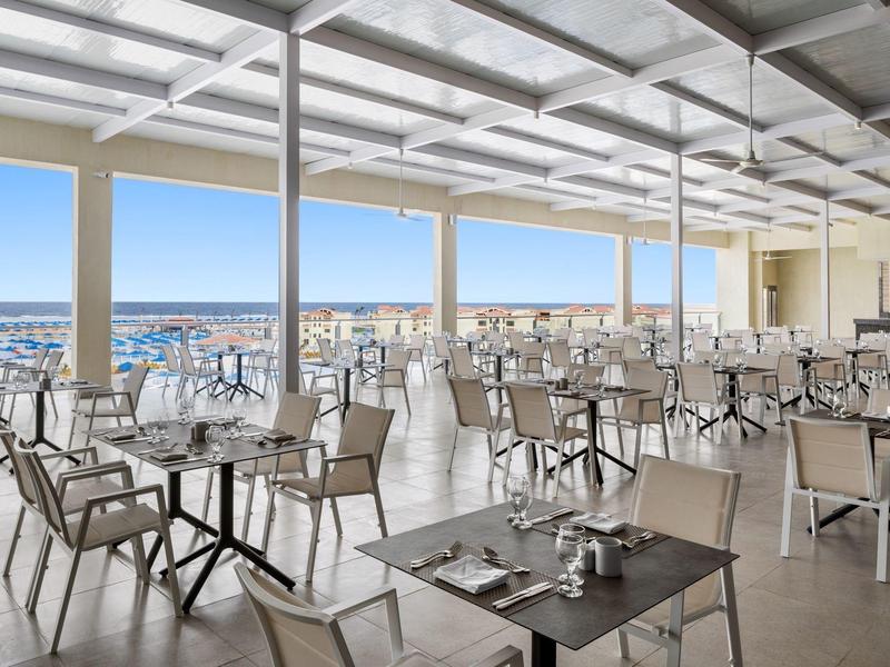 Modernes Restaurant mit großem Fenster und Blick auf die Stadt und das Meer.