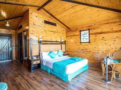 Cozy wooden room with double bed, chairs, and large window letting in natural light.