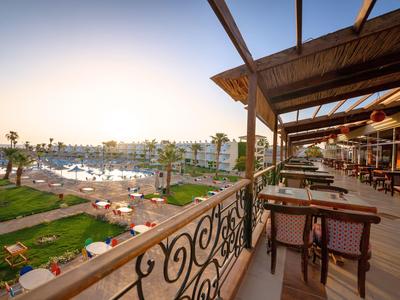 Balkon mit Sitzgelegenheiten und Blick auf eine Marina mit Booten und Sonnenuntergang.