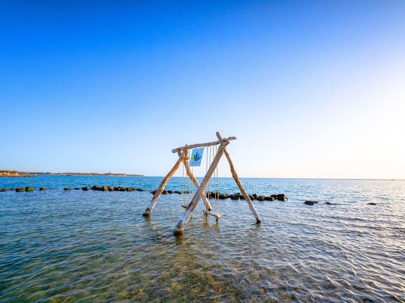Swing over shallow water with clear sky at the sea