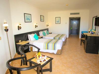 Jasny pokój hotelowy z dwoma łóżkami, telewizorem, miejscem do siedzenia i biurkiem.