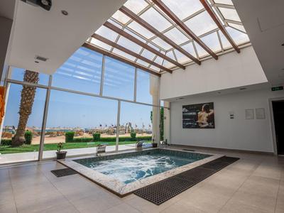 Nowoczesne wewnętrzne jacuzzi z szklanym dachem i widokiem na tropikalny ogród.