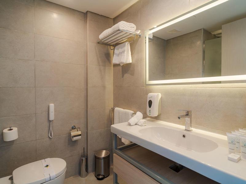 Nowoczesna łazienka z dużym lustrem, umywalką i toaletą w pokoju hotelowym.