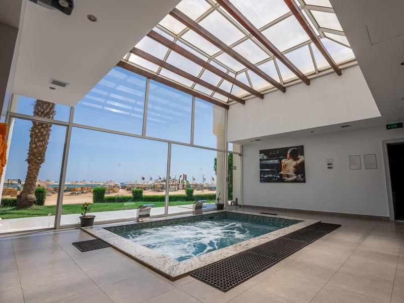 Nowoczesne wewnętrzne jacuzzi z szklanym dachem i widokiem na tropikalny ogród.