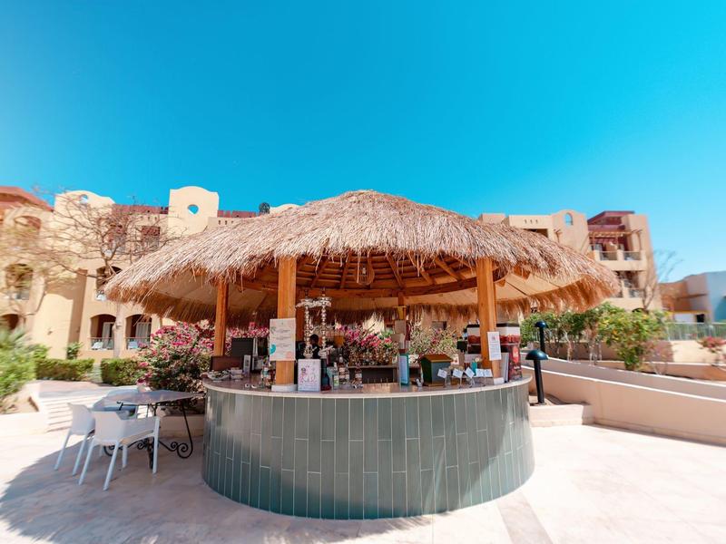 Okrągły, otwarty bar plażowy z bambusowym dachem i miejscami do siedzenia pod błękitnym niebem.