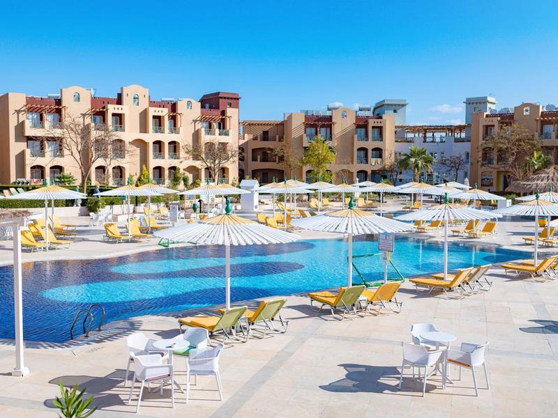 Duży hotelowy basen z wieloma leżakami i parasolami w słoneczny dzień