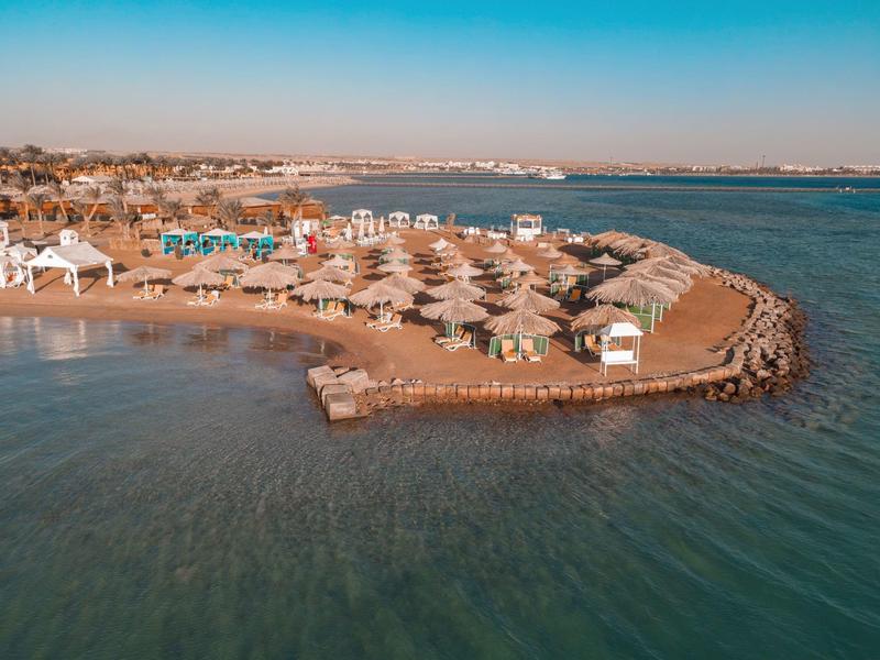 Ośrodek nadmorski z parasolami na półwyspie nad spokojnym, niebieskim morzem.