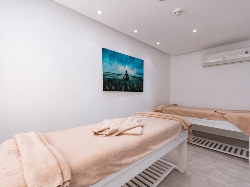 Dwa stoły do masażu z beżowymi ręcznikami w jasnym, nowoczesnym pomieszczeniu.