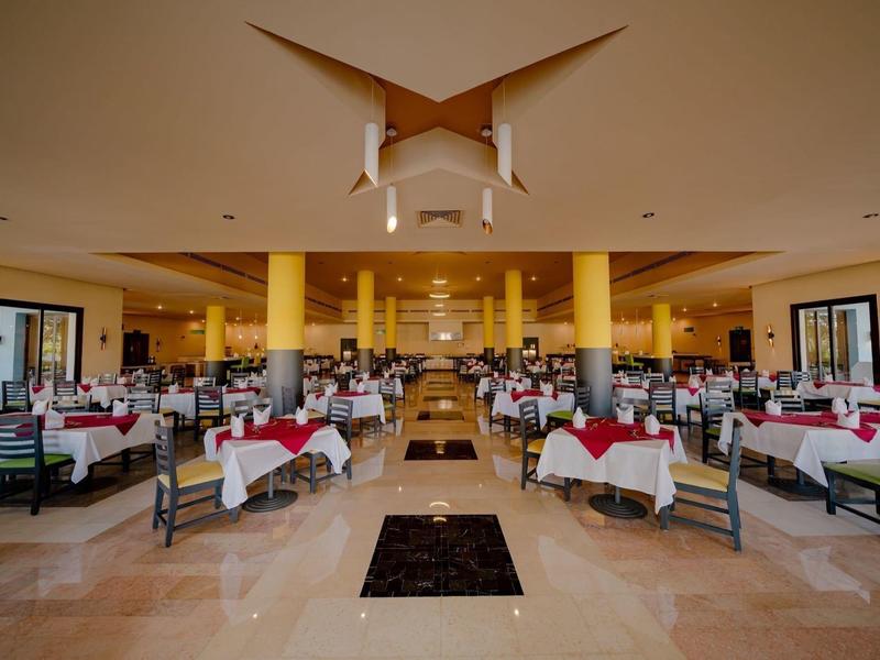 Duża restauracja z nakrytymi stołami i żółtymi kolumnami w eleganckim otoczeniu.