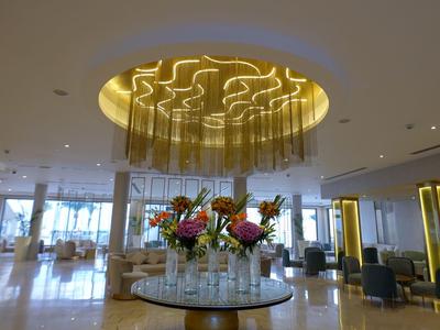 Modern hotel lobby area with round bar and elegant chandelier.