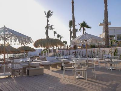 Modern outdoor hotel area with seating and sun umbrellas under clear sky.