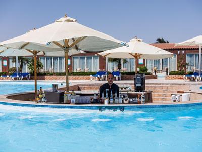 Poolbar met parasols en barkeeper, omgeven door hotelgebouwen.