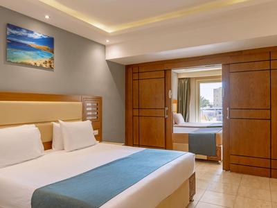 Nowoczesny pokój hotelowy z podwójnym łóżkiem i widokiem przez drewniane przesuwne drzwi na taras.