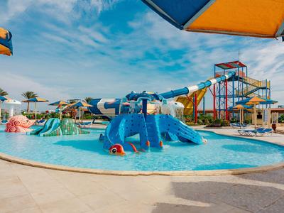 Children's play area with water slides and pools at a hotel resort under a sunny sky.