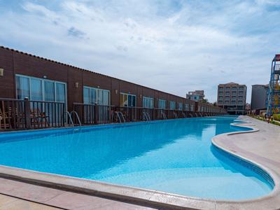 Modern outdoor pool next to a hotel building under a cloudy sky.