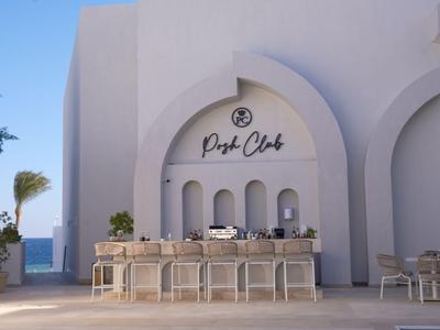 Modern outdoor bar area with white arches and sea view at a hotel.