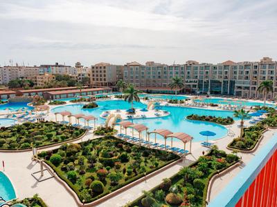 Grande resort con più piscine e aree verdi sotto un cielo nuvoloso.
