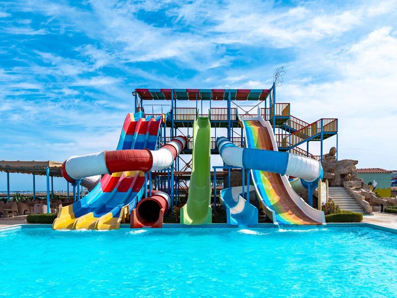 Toboggans aquatiques colorés dans une piscine sous un ciel bleu dans une station de vacances.
