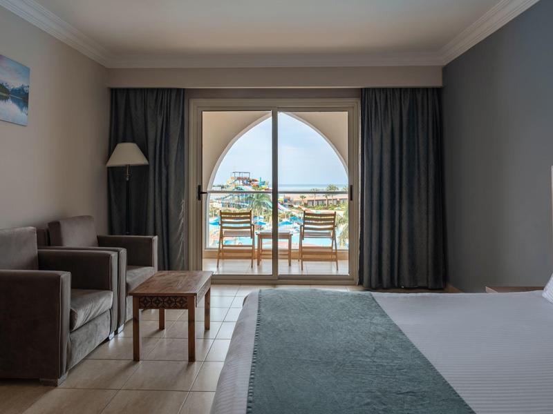 Chambre d'hôtel lumineuse avec balcon et vue sur la mer.