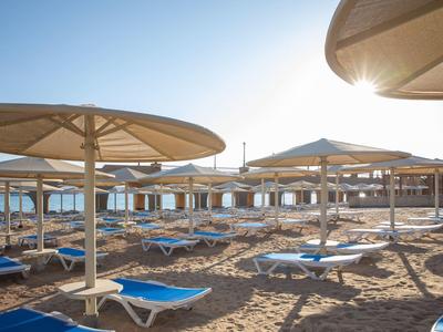 Beach with sun loungers and large umbrellas under clear sky