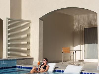 Person relaxing on a lounge chair in the hotel pool area.