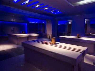 Dimly lit spa room with massage tables and soft blue lighting.