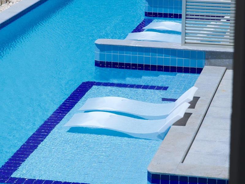 Modern pool area with built-in hot tub and steps in clear blue water.