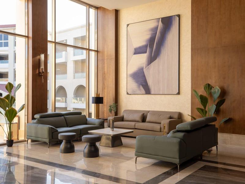Modern hotel lounge area with large windows, sofas, and contemporary artwork.
