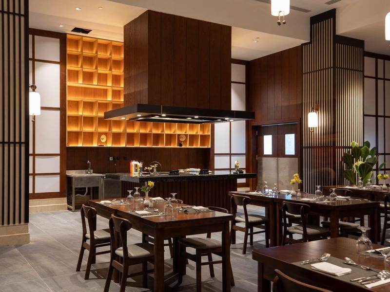 Modern hotel restaurant interior with dark wood furniture and warm lighting.