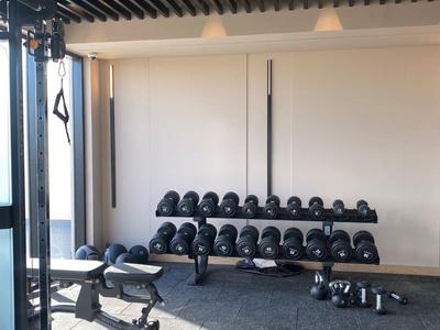 Gimnasio luminoso con mancuernas, banco de entrenamiento y equipo moderno en un hotel.