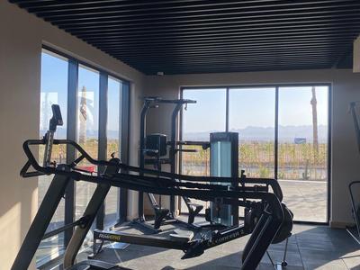 Gimnasio luminoso con equipo moderno y grandes ventanas con vistas.