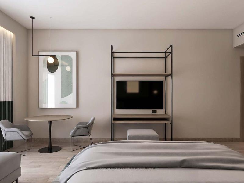 Modern eingerichtetes Hotelzimmer mit Bett, Schreibtisch, zwei Stühlen und Kunst an der Wand.