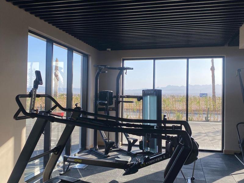 Heller Fitnessraum mit Laufband und großen Fenstern mit Blick ins Freie.