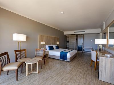 Chambre d'hôtel spacieuse avec lit double, coin salon, bureau et design moderne.