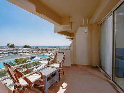 Balcon avec deux chaises et une table donnant sur la piscine et la mer dans un hôtel.