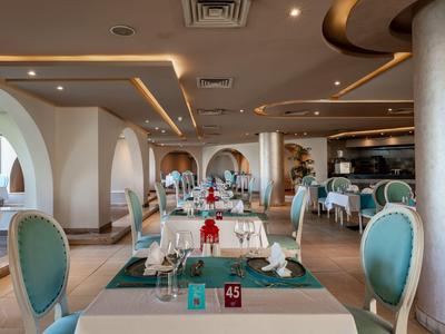 Elegantes Hotelrestaurant mit runden Sesseln und gedeckten Tischen unter warmem Deckenlicht.