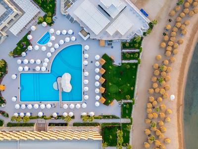 Vue drone d'une piscine d'hôtel avec parasols et plage adjacente