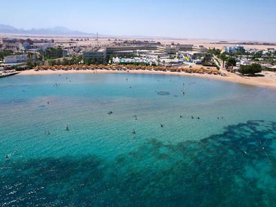 Eau turquoise claire à la plage avec des hôtels et des montagnes en arrière-plan.