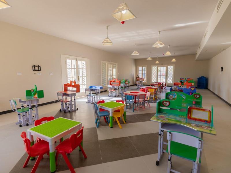 Salle de classe colorée et spacieuse avec petites tables et chaises pour enfants.