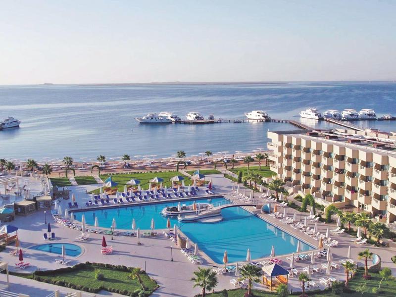 Complexe hôtelier avec plusieurs piscines et vue sur la mer sous un ciel dégagé.