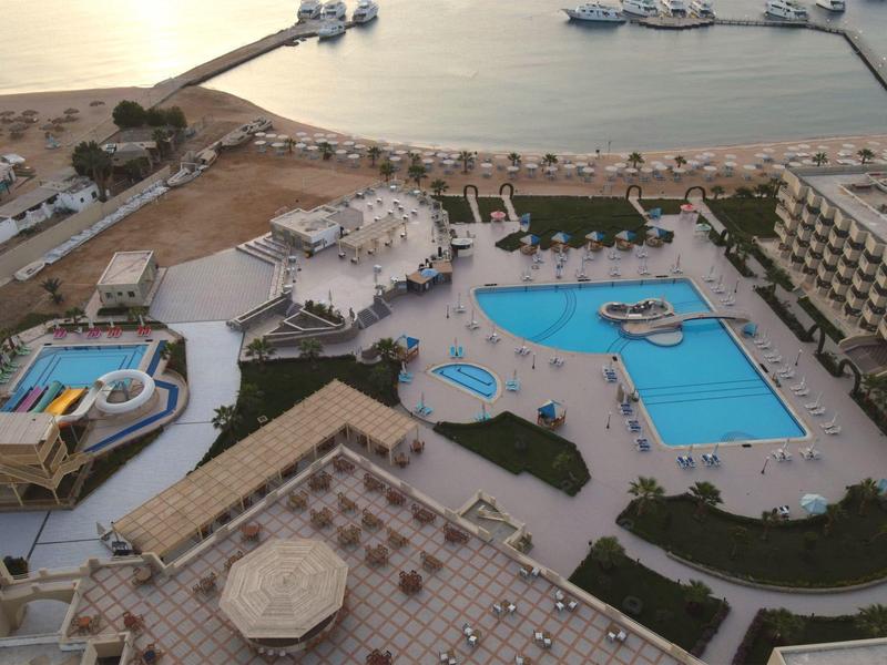 Vue aérienne d'un grand hôtel avec plusieurs piscines et vue sur la mer.