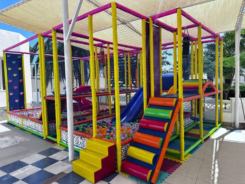 Structure de jeu colorée pour enfants avec toboggan et éléments d'escalade dans une aire couverte.