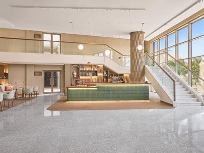 Světlá hotelová relaxační zóna s moderním interiérem a velkými okny.