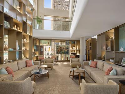 Moderní světlý hotelový salonek s pohodlnými sedacími kouty a velkými okny.