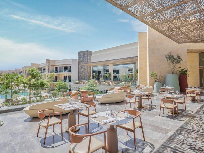 Terrasse d'hôtel moderne avec sièges élégants et vue sur l'eau et les bâtiments.